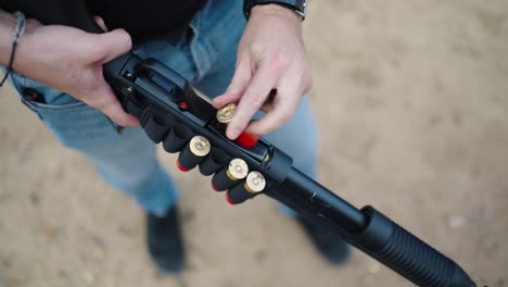 person reload new shells into shotgun weapon, olesko shooting range