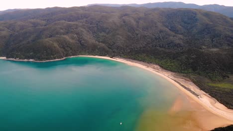 Eine-Yacht-Segelt-In-Der-Onetahuti-Bucht,-Ein-Langer-Sandstrand-Zeigt-Eine-Paradiesische-Luftaufnahme