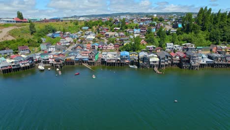 panoramic aerial view establishing over the stilt houses of castro in chiloe, parallax effect, sunny day, high tide