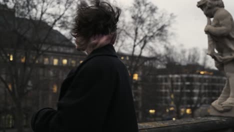 young woman in a black coat standing on a terrace and smoke-1