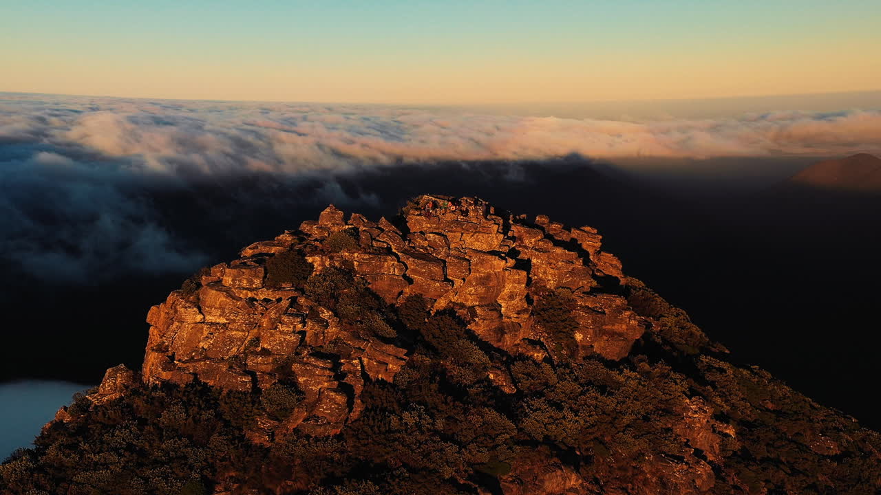 vista aérea alrededor de la gente, en la cima de la montaña del monte hassell, por encima de las nubes, durante la puesta de sol, en el oeste de australia - órbita, disparo de drones