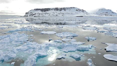 Sun-reflecting-off-an-arctic-landscape-moving-through-sea-ice-in-Lomfjorden-in-Svalbard-Archipelago-Norway