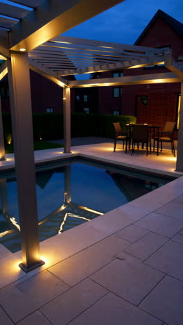 modern backyard pool and pergola at night