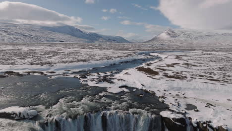 Aerial-View-of-North-Iceland,-Snow-Capped-Landscape,-Glacial-River-and-Waterfall-on-Sunny-Winter-Day