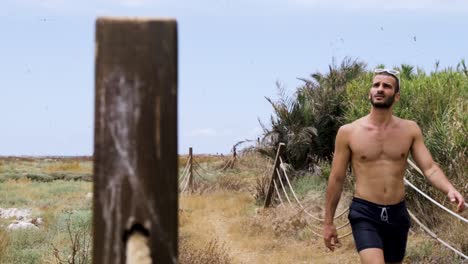 young caucasian strong healthy lebanese man hiking on dirt trail wearing shorts and shirtless, tripoli, lebanon, close up slow motion