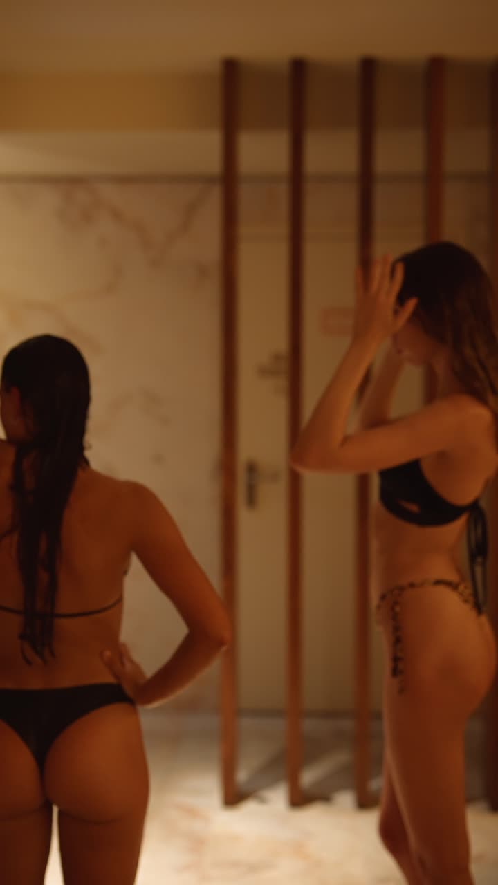 Due donne in bikini che stanno in piedi e parlano in una spa calda