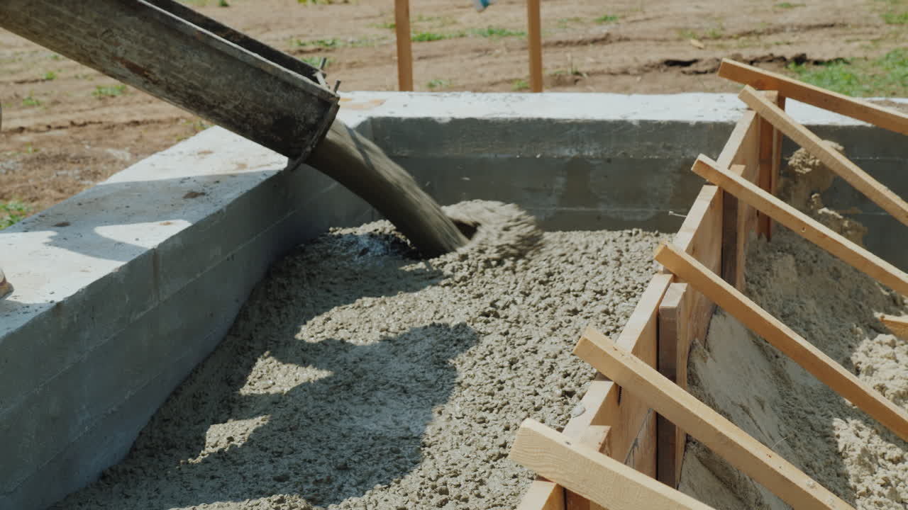 trabajar con hormigón en el sitio de construcción los trabajadores toman hormigón en un molde de madera manual pesado la