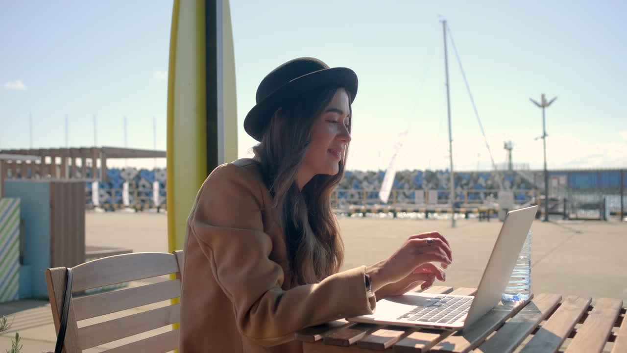 mujer trabajando en una computadora portátil en un café al aire libre cerca de la playa