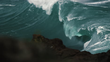 heavy wave breaking behind the rocks