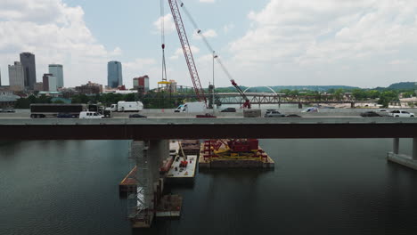 Vehicles-transit-back-and-forth-across-Arkansas-River-Bridge-I-30-highway-construction,-Little-Rock,-AR---Aerial-slide-right