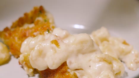 creamy macaroni cheese being placed on a plate with serving spoon in slow motion. pasta based main dinner dish