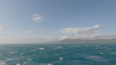 sea swell increases as cloud-covered land appears during cook strait crossing from south island to north island, new zealand