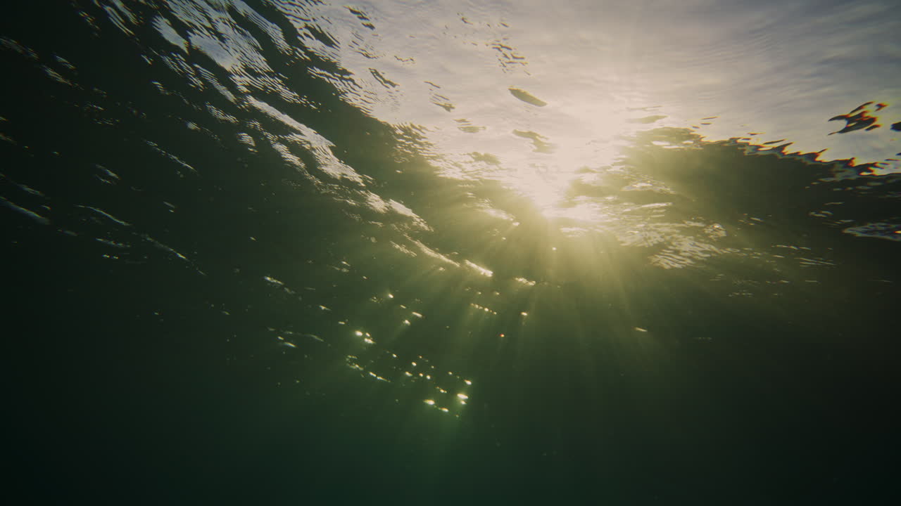 Ripples in ocean surface catch sparkling rays as ocean wave breaks