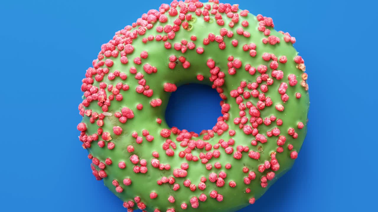 primer plano de anillo de rosquilla dulce giratorio con glaseado verde y cubierta de pastel rosa. cámara roja de dragón 4k