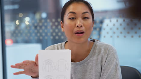 asian fashion designer in clothing business discussing designs sitting at table in office meeting room