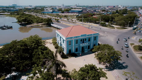 Vista-Aérea-De-La-Casa-Azul,-Cariñosamente-Llamada-Ministerio-De-Cultura,-Adorna-El-Paisaje-Como-Una-Joya-Cultural,-Una-Oda-A-La-Tradición-Y-La-Innovación,-Complementada-Con-El-Bullicioso-Paisaje-Urbano-Al-Fondo