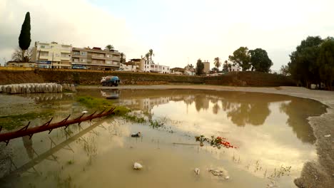 big puddle under old walls of nicosia far buildings and cars drive