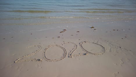 turning steadicam shot of twenty twenty written in the sand