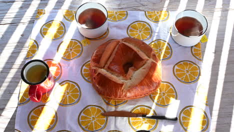 Vista-De-Una-Fiesta-De-Té-En-Una-Mesa-De-Madera,-Tazas-De-Té-Calientes-Y-Un-Brioche