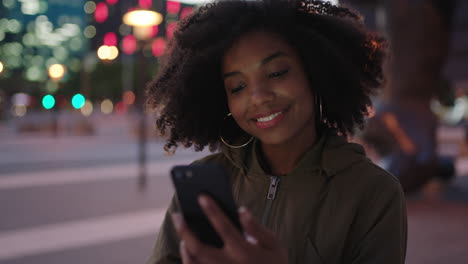 Porträt-Einer-Stilvollen-Jungen-Schwarzen-Frau-Mit-Afro-SMS,-Die-Nachts-In-Der-Stadt-Mit-Smartphone-Mobiltechnologie-Surft