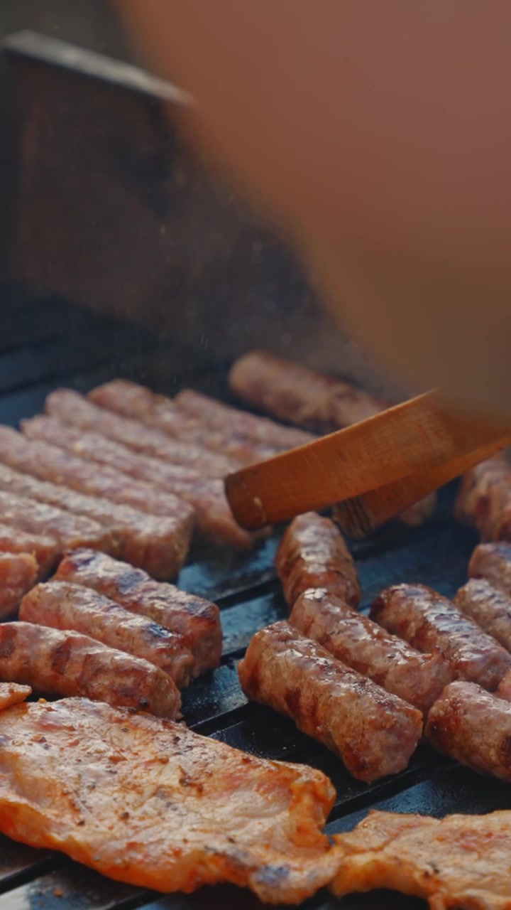 Carne e salsicce sfrigolanti alla griglia cuociono su una griglia per barbecue in questo video verticale gustoso, perfetto per storie di cibo o reel ottimizzati per dispositivi mobili