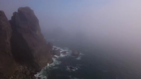 aerial: slow push past an oregon coastline rock formation shrouded in fog