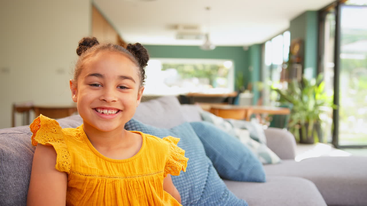 retrato de una chica sonriente relajándose sentada en el sofá en casa