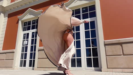 woman in flowing beige dress posing in front of building