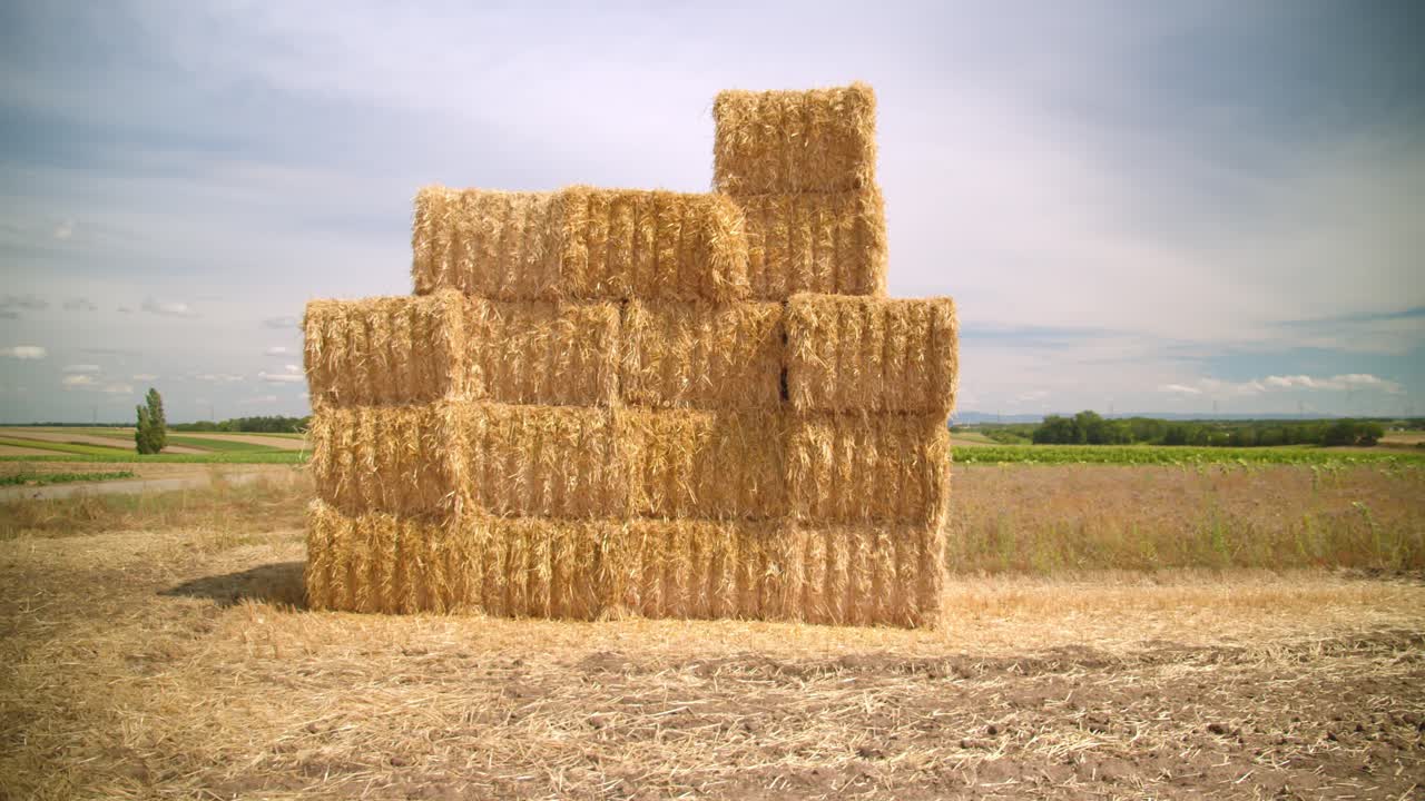 apilados de balas de heno cuadradas en las tierras de cultivo rurales en un día soleado