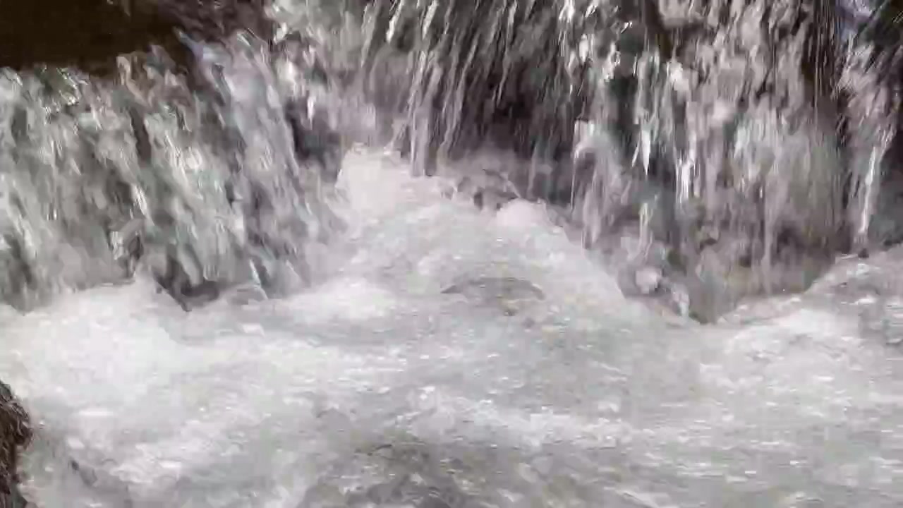 Primo piano di acqua impetuosa che scorre su rocce in un ruscello
