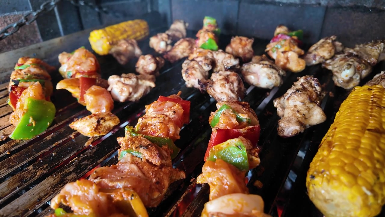 Spiedini di carne e mais alla griglia su un barbecue a carbone.