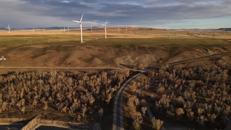 cinematic aerial footage of wind turbines in canada during a sunrise that illuminates the rocky mountains in the background