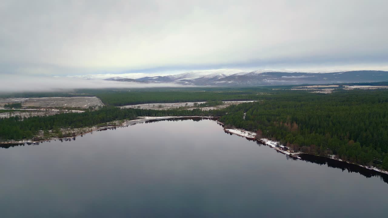Sorvolo aereo di Loch Insh, Scozia, verso montagne innevate all'orizzonte