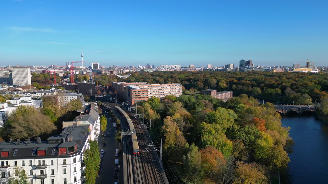 Scenic view of a train crossing a bridge over a river in berlin, surrounded by vibrant autumn foliage. Best aerial view flight overflight flyover drone