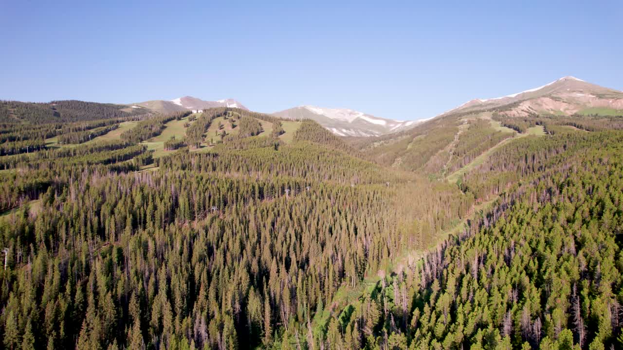Aerial footage of ski slopes in Breckenridge Colorado. Camera is flying over ski paths and trees.