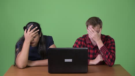 young multi-ethnic business couple together against green background