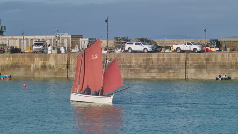 traditional cornish red sailboat in the harbour of st