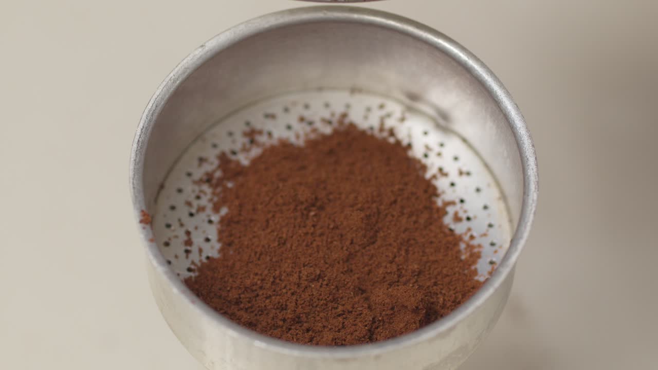 Coffee grounds falling onto a metal tray, showing a close-up view of the process