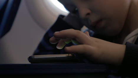 Close-up-view-of-small-boy-playing-with-smartphone-on-the-table