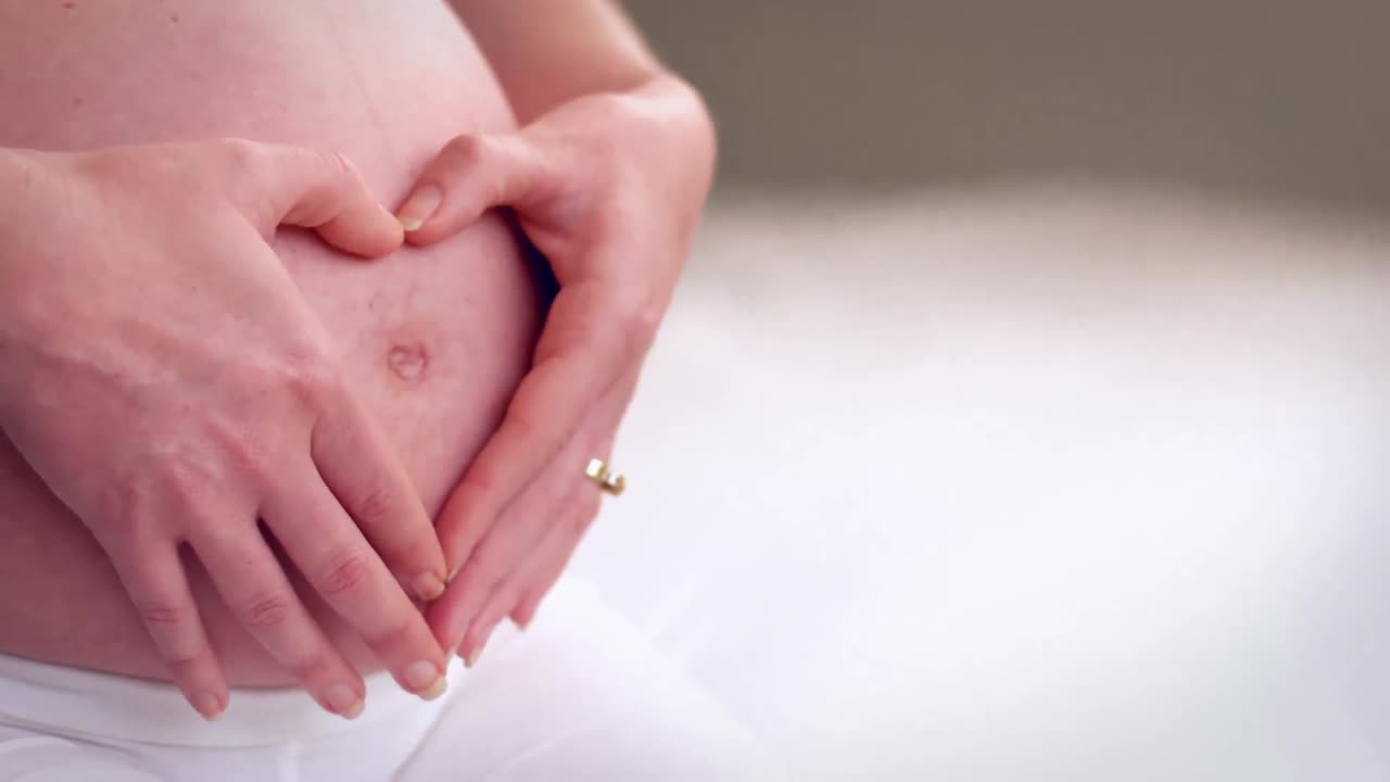 Donna incinta che forma un cuore con le mani sulla pancia