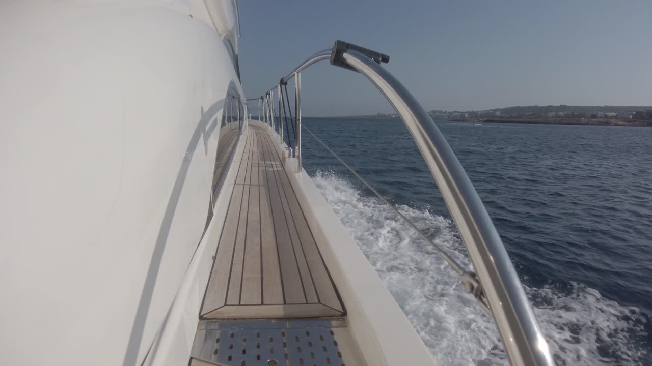 Vista lungo il fianco di uno yacht del passaggio stretto sul ponte e della scia della barca mentre sfreccia sull'acqua.