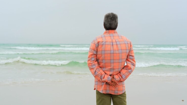 Rear view of active senior African American man with hand behind back standing on the beach 4k