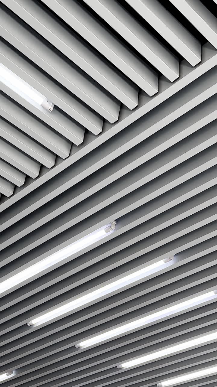 Decoration planks on the ceiling with led lamps for white day illumination. Black and white image. Low angle view. Vertical video