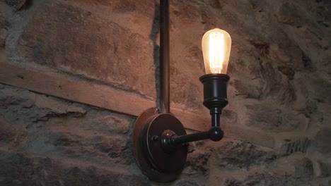 slowmo - alte antike lampe auf neuseeländischer schiefersteinmauer im luxusrestaurant