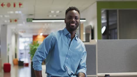 Video-Eines-Glücklichen-Afroamerikanischen-Geschäftsmannes,-Der-Im-Büro-In-Die-Kamera-Blickt