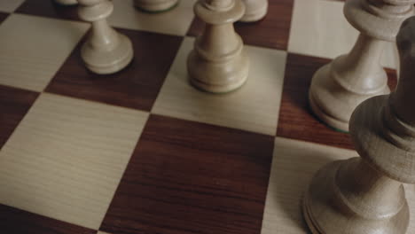 closeup of player hand moves white knight chess piece, looking down perspective