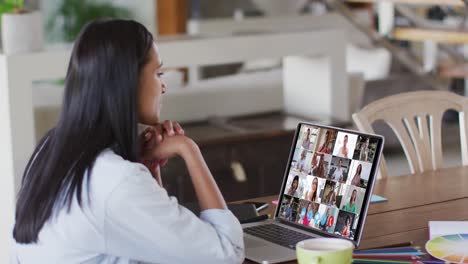 mujer caucásica usando una computadora portátil en una videollamada con colegas que trabajan desde casa