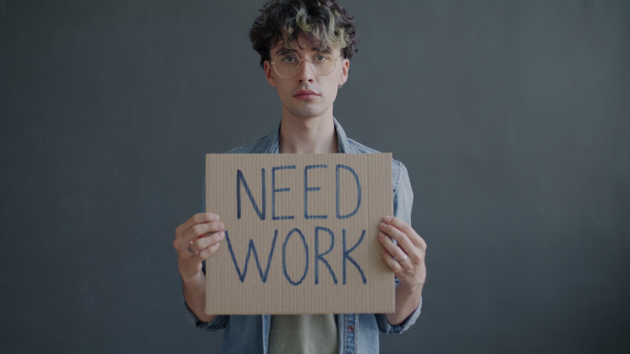 Man Holding a Cardboard Sign Saying "Need Work"