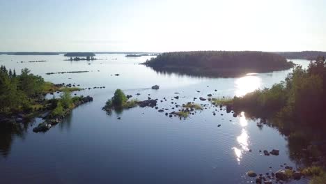 Aerial-tracking-drone-shot,-following-a-motorboat-driving-between-small-islands-in-Northern-Europe-on-a-sunny-summer-day