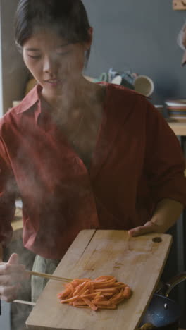 woman cooking carrots in kitchen